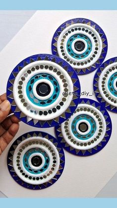 four blue and white skateboard wheels are being held by someone's hand over a piece of paper