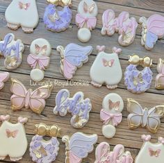 many decorated cookies are displayed on a wooden table with butterflies and other decorations in pastel colors