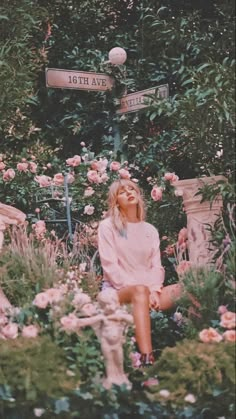 a woman sitting on the ground in front of flowers