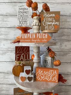 a three tiered display with pumpkins and other fall decorations on top of it