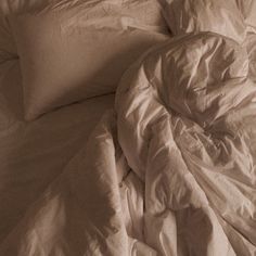 an unmade bed with white sheets and pillows