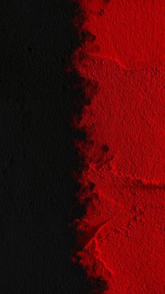 a red and black wall with some paint on it's side in the dark