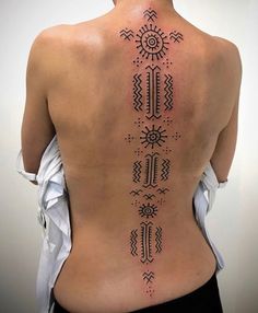 the back of a woman's body with an intricate tattoo design on her lower back