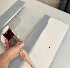 a person is using a brush to paint a piece of wood