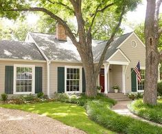 a house with green shutters and trees in the front yard