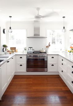 a kitchen with white cabinets and wood flooring, including an oven in the center