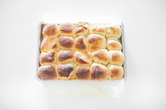 a pan filled with hot cross buns on top of a white counter next to a knife