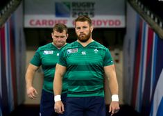 two men in green jerseys are walking through the tunnel with their hands on their hips