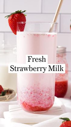 a strawberry milkshake in a glass with strawberries on the side