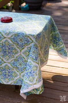 a blue and green table cloth with a red object on it sitting on a wooden deck