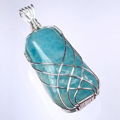 a wire wrapped pendant is shown on a white surface with a light blue stone in the center