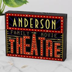 a wooden sign that says anderson family movie theatre on it's side next to a potted plant