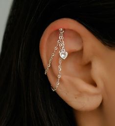 a close up of a person's ear with chains attached to it and a heart on the side