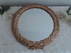 a round mirror sitting on top of a table next to white flowers and greenery