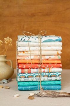 a stack of folded fabric sitting on top of a table next to a potted plant