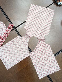 two pieces of paper sitting on top of a wooden floor next to scissors and tape