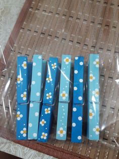 four pieces of blue paper with white and yellow flowers on them are wrapped in clear cellophane