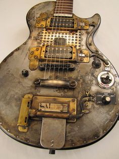 an old guitar that is sitting on top of a stand with some wires attached to it