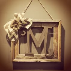 a wooden sign with a flower hanging from it's side and the letter m is made out of wood