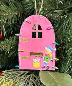 a pink door ornament hanging from a christmas tree