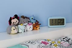 there are many stuffed animals on the shelf next to the alarm clock that reads 10 20