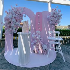 two white chairs sitting next to each other on top of a stone floor covered in flowers