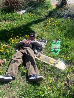 a man laying in the grass with his feet on a skateboard