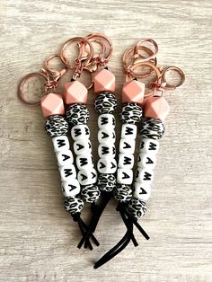 four keychains with pink and black designs on them sitting next to each other