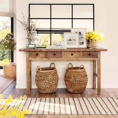 two baskets sit on top of a wooden table in front of a mirror and window