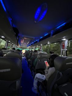 the inside of a bus with people sitting in seats and lights on it's ceiling