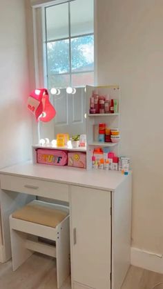 a small white desk with a mirror and lights on it in front of a window