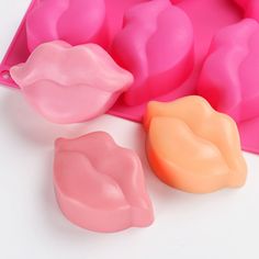 two pink and one orange lips are next to a plastic mold mold tray on a white surface