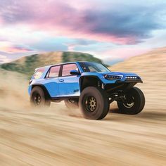 a blue four - doored truck driving through the desert