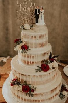 a three tiered wedding cake with red flowers on the top and white icing