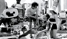 black and white photograph of people on the beach with film equipment in front of them