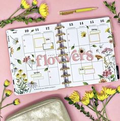 a planner with flowers on it sitting next to a purse and some yellow flower petals