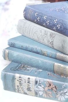 four blue books stacked on top of each other in front of a white tablecloth