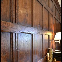 a wooden paneled wall with a lamp on the end table in front of it