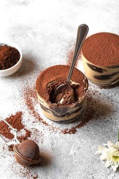 two bowls filled with chocolate ice cream on top of a white table next to flowers