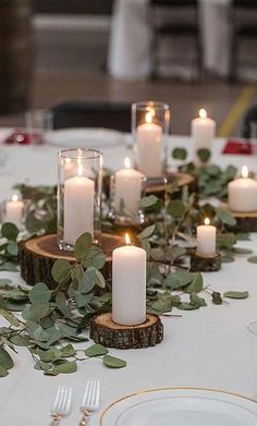 a table topped with lots of candles and greenery