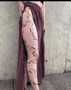 a woman's legs with tattoos on them are shown in front of a wall