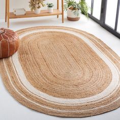 a round rug with white and tan stripes on the floor in front of a window