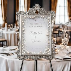 a wedding sign sitting on top of a table with white linens and place settings