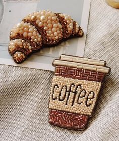 two brooches are sitting on top of a piece of fabric next to each other