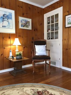 a living room with wood paneling and a chair in the corner next to a lamp