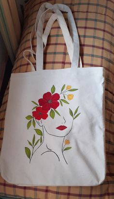 a white bag with red flowers on it sitting on top of a plaid bed sheet