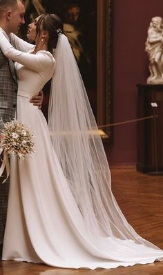 a bride and groom standing together in front of a painting on the wall with their arms around each other