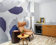 a chair and table in front of a wall with an abstract painting on the wall