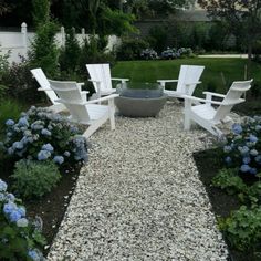 an outdoor patio with white chairs and gravel