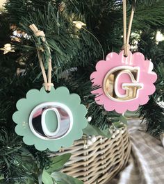 two ornaments hanging from a christmas tree in the shape of letters g and q, on top of a basket